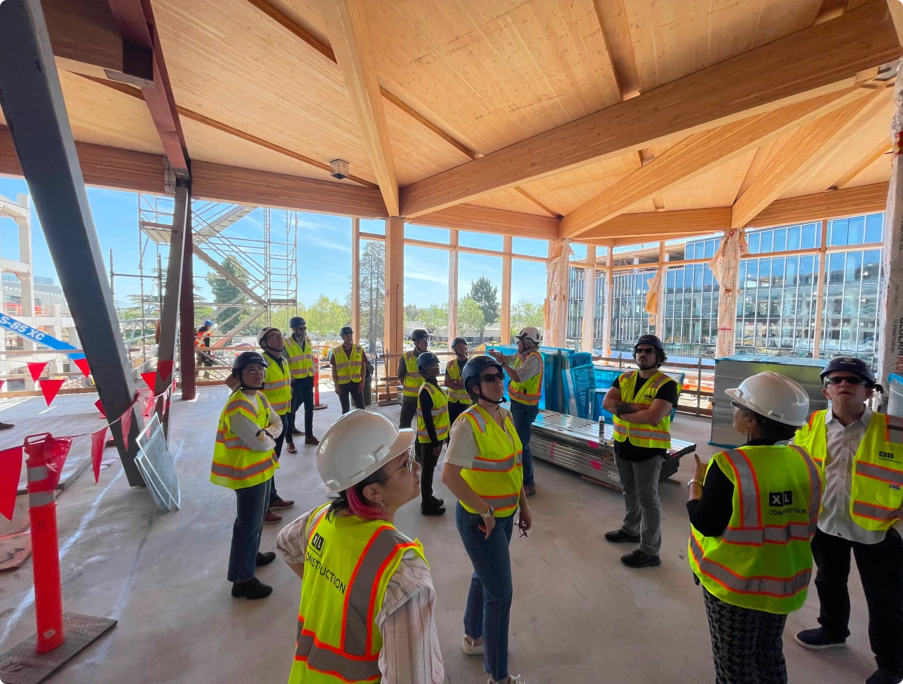 Construction site tour inside timber framed office building with workers in safety vests